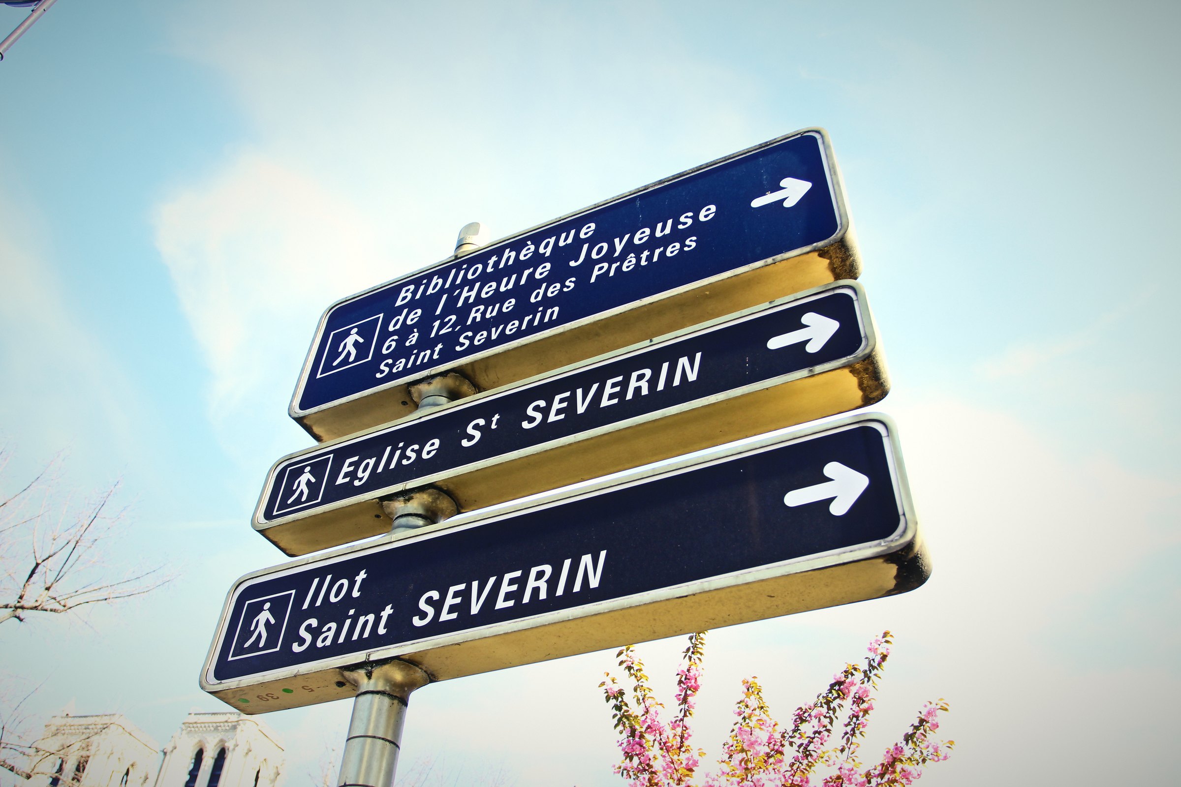 Three brown and blue Paris direction signs with arrows pointing right toward Saint-Séverin.