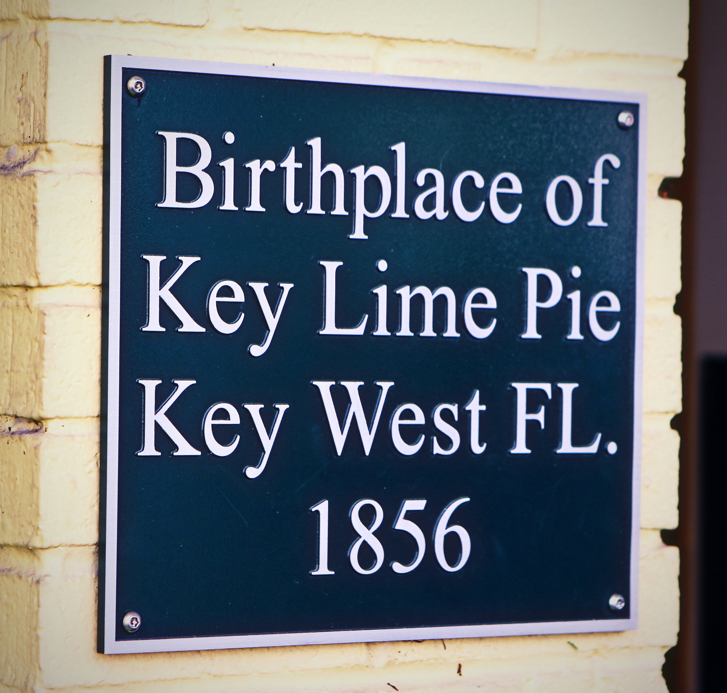 Dark green plaque reading Birthplace of Key Lime Pie, Key West FL. 1856.