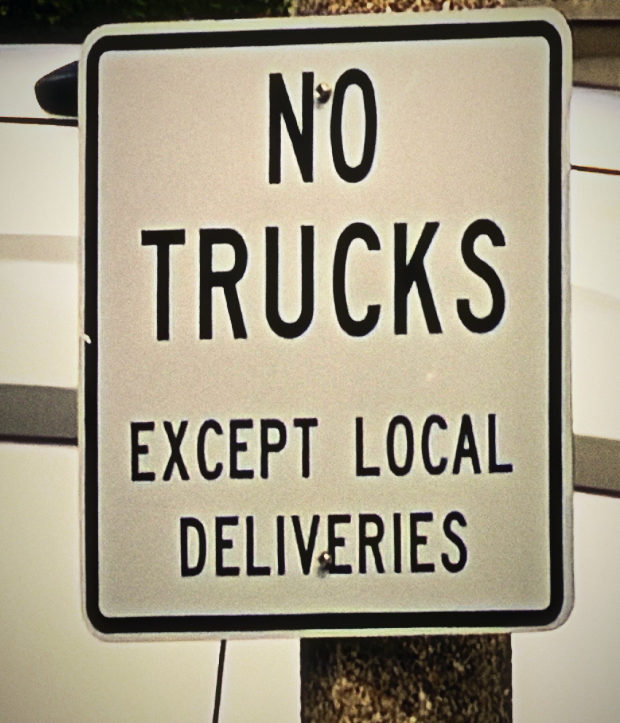 Black and white sign reading No Trucks Except Local Deliveries.