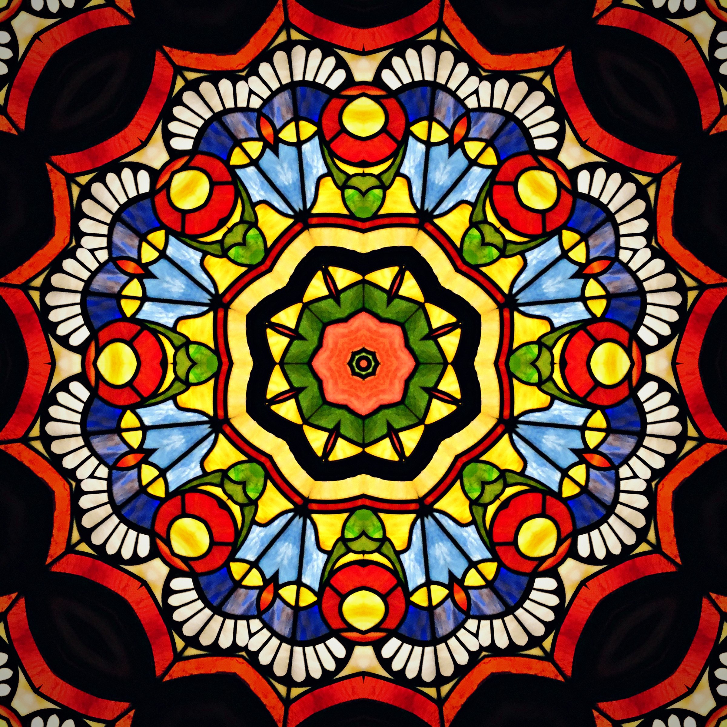 Kaleidoscope mandala in red, gold and cobalt built from stained glass.