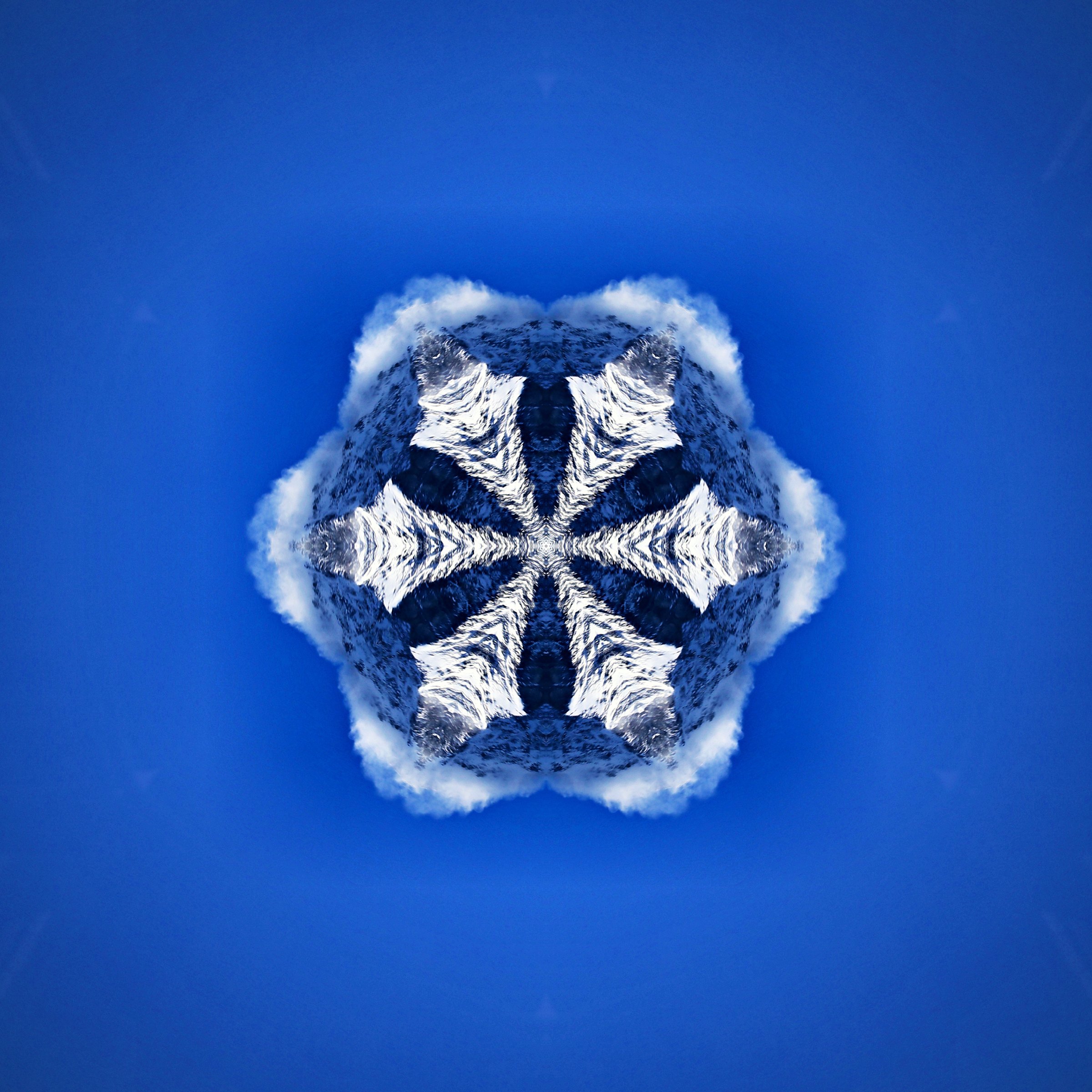 White snowflake shape on a deep blue field, made from mountain snow.