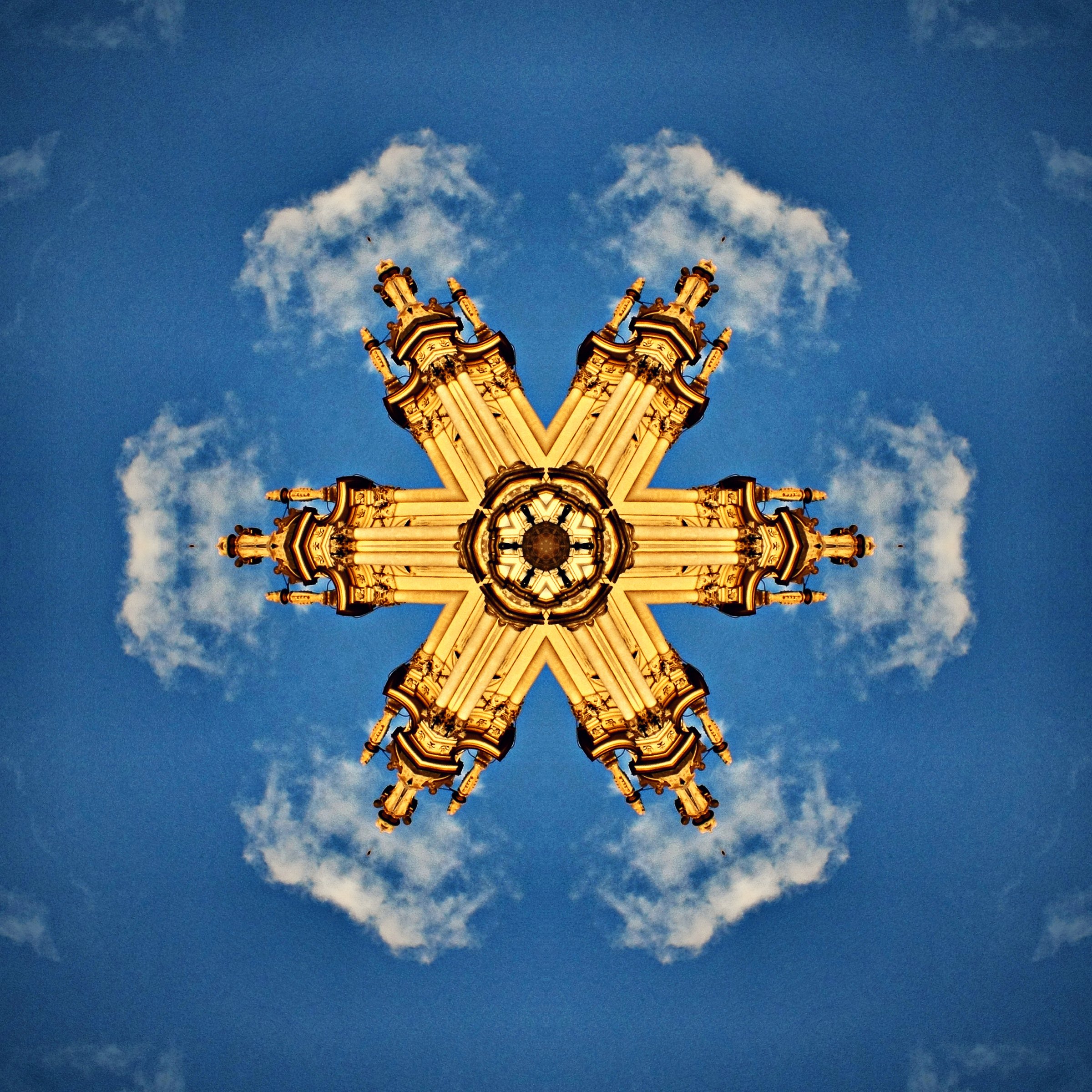 Gold arches radiating against a bright blue sky and white clouds.