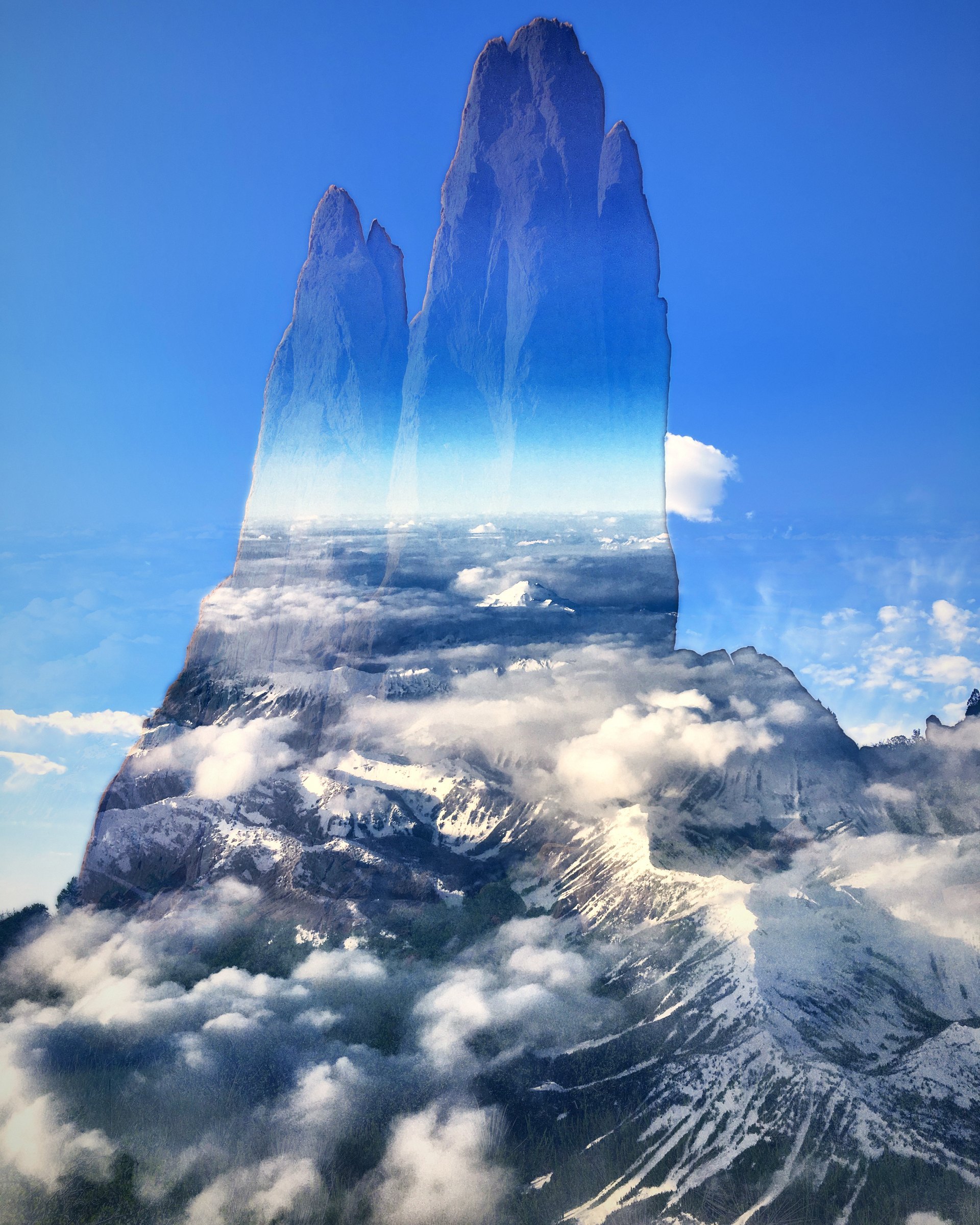 Twin rock spires filled with a sea of clouds and mountain peaks against blue sky.