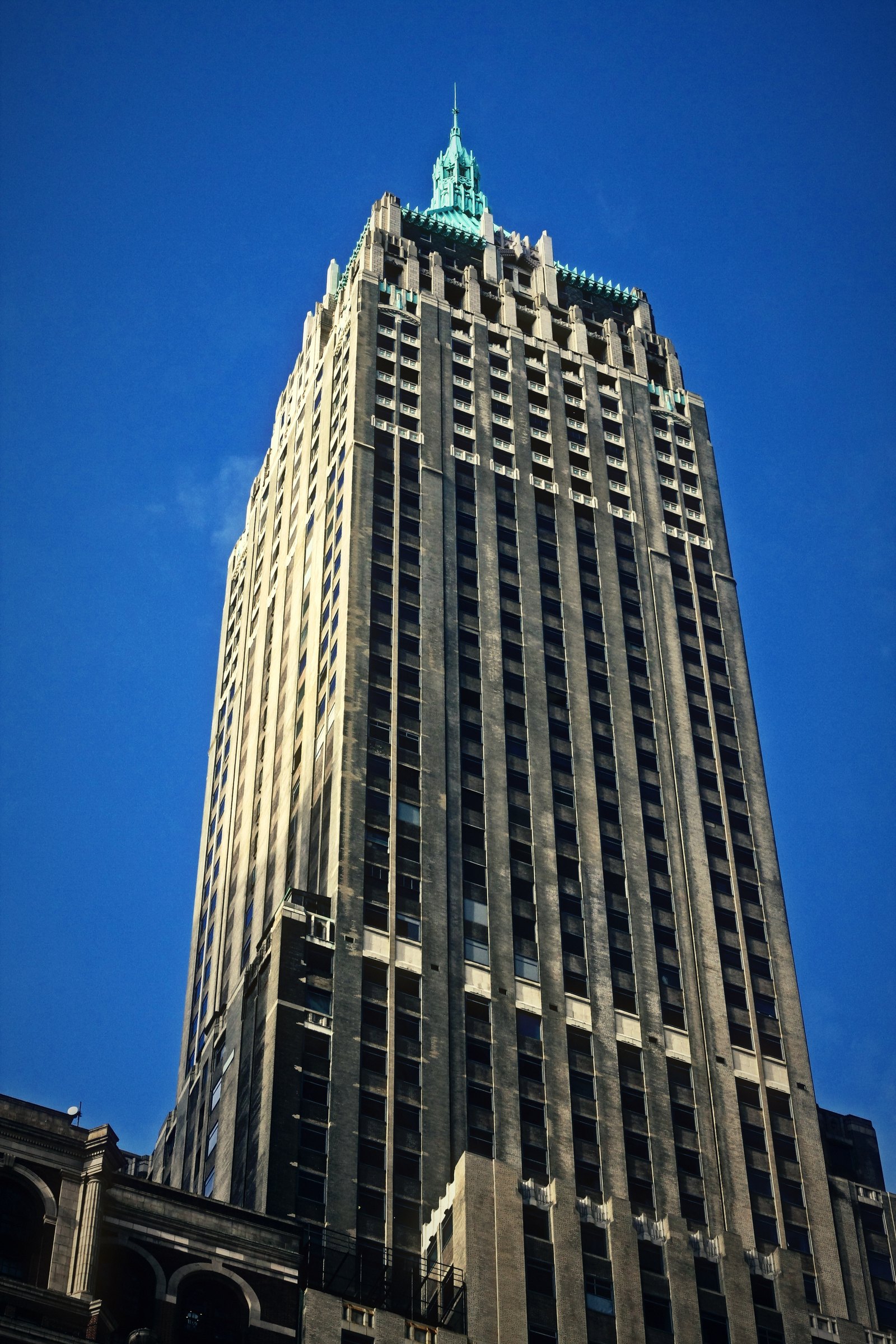 Art Deco skyscraper with a green crown against a cobalt sky.