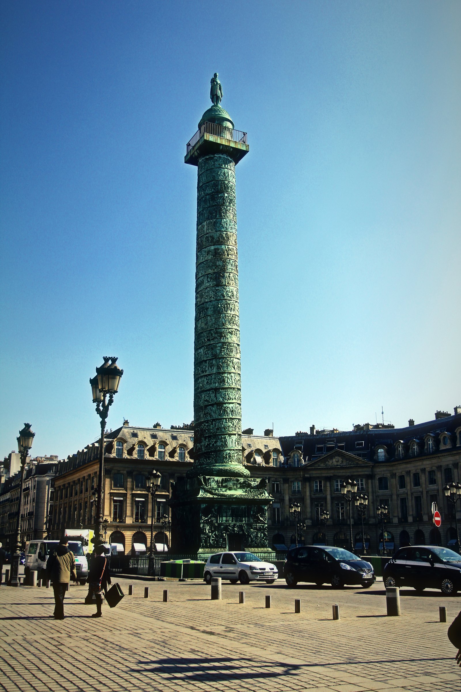 Bronze column rising from a stone square lined with classical buildings.
