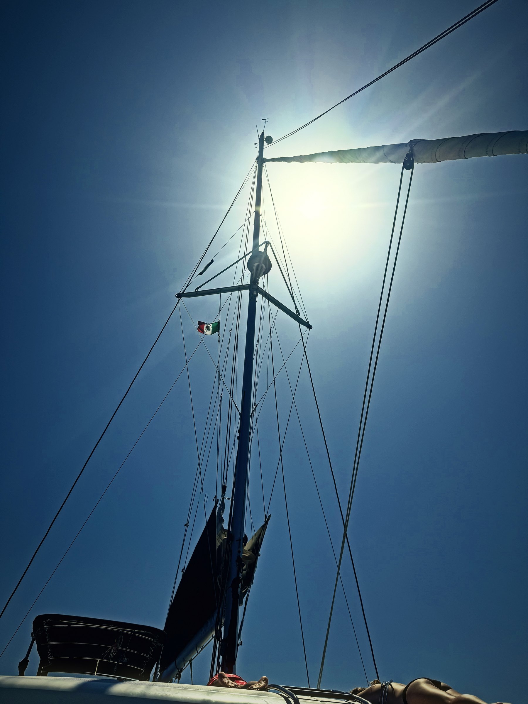Sailboat mast and rigging pointing straight into a bright sun.