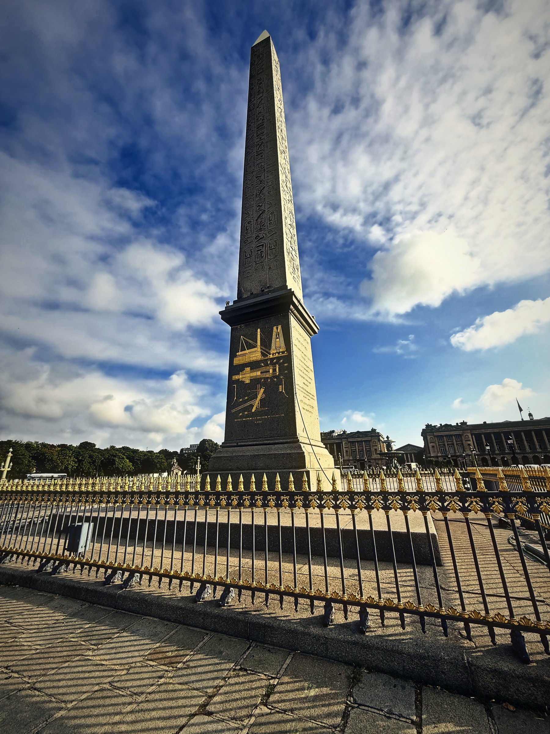Stone obelisk with gold hieroglyphs under a big sky of moving cloud.