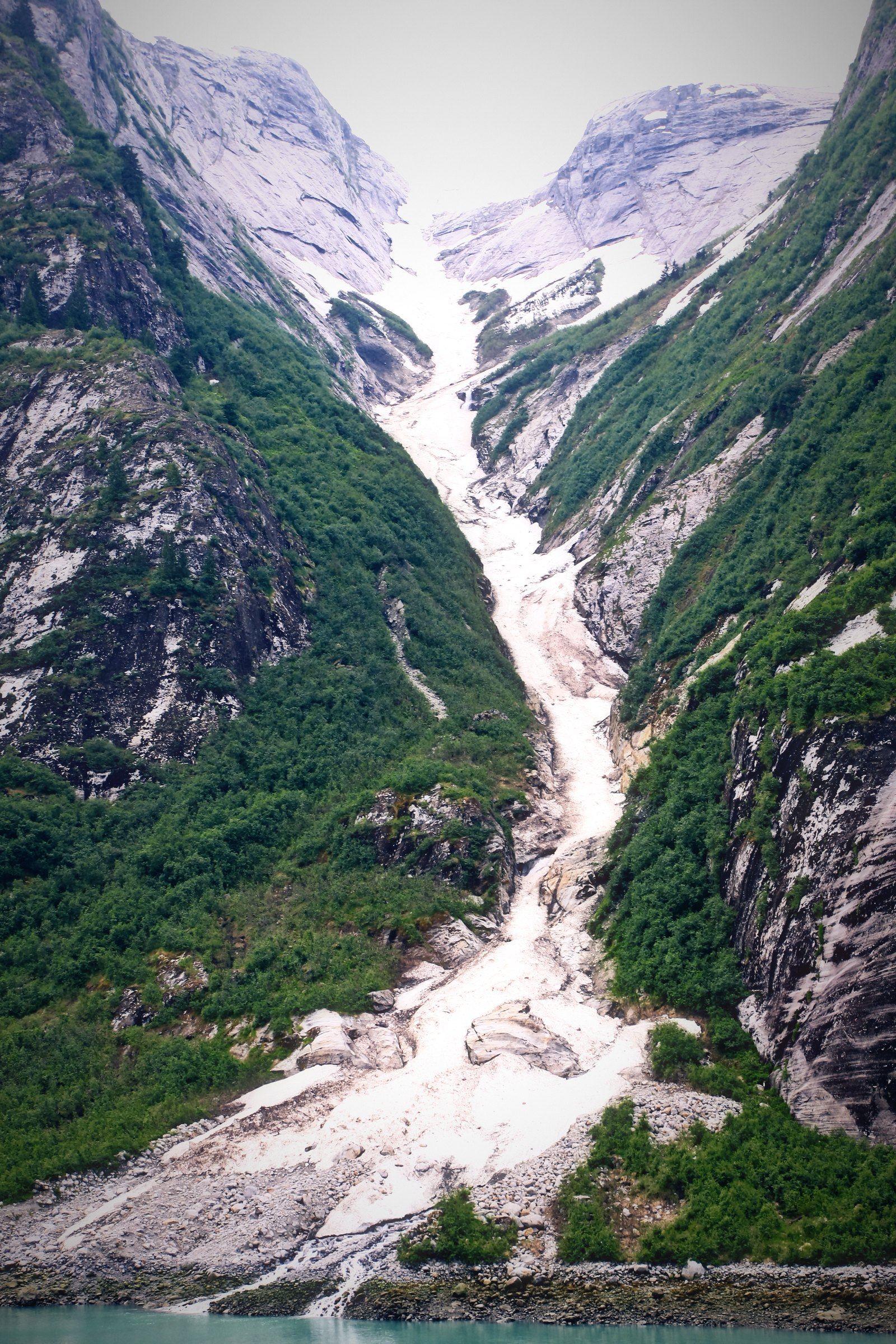 A long white snow-and-water chute running down a steep green valley.