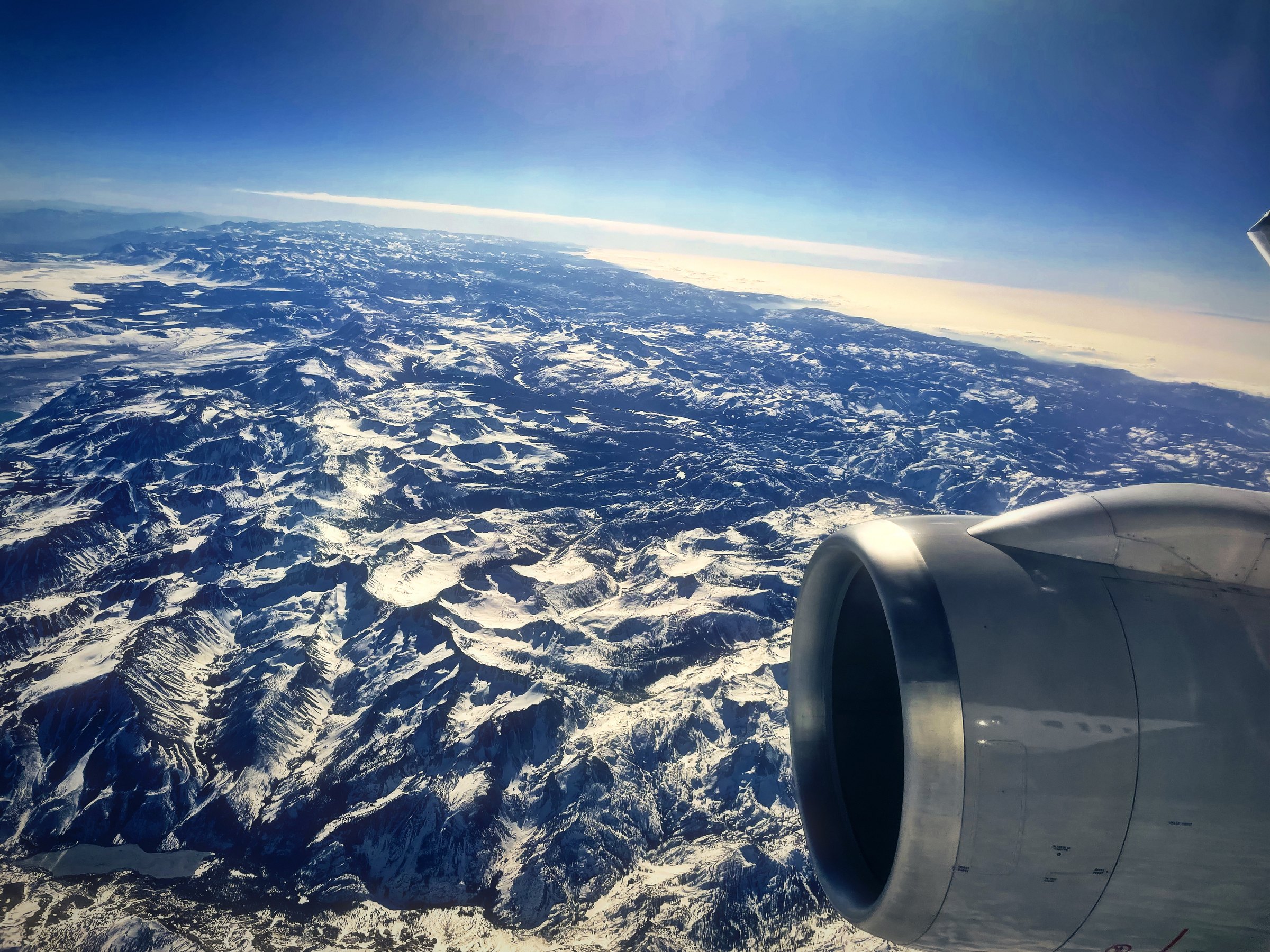 Jet engine over a range of snow-veined mountains stretching to the horizon.