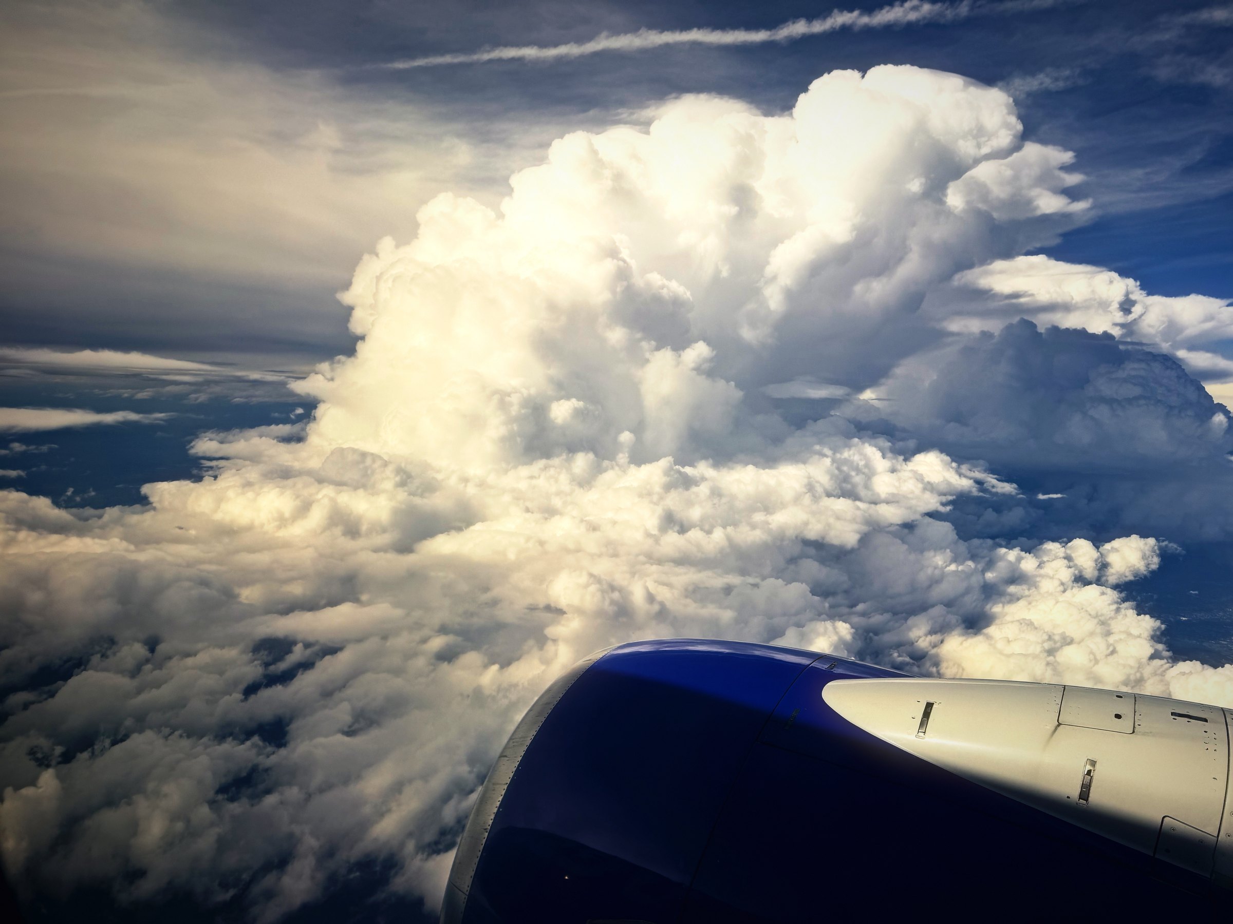 A towering white thunderhead building beside a jet engine.