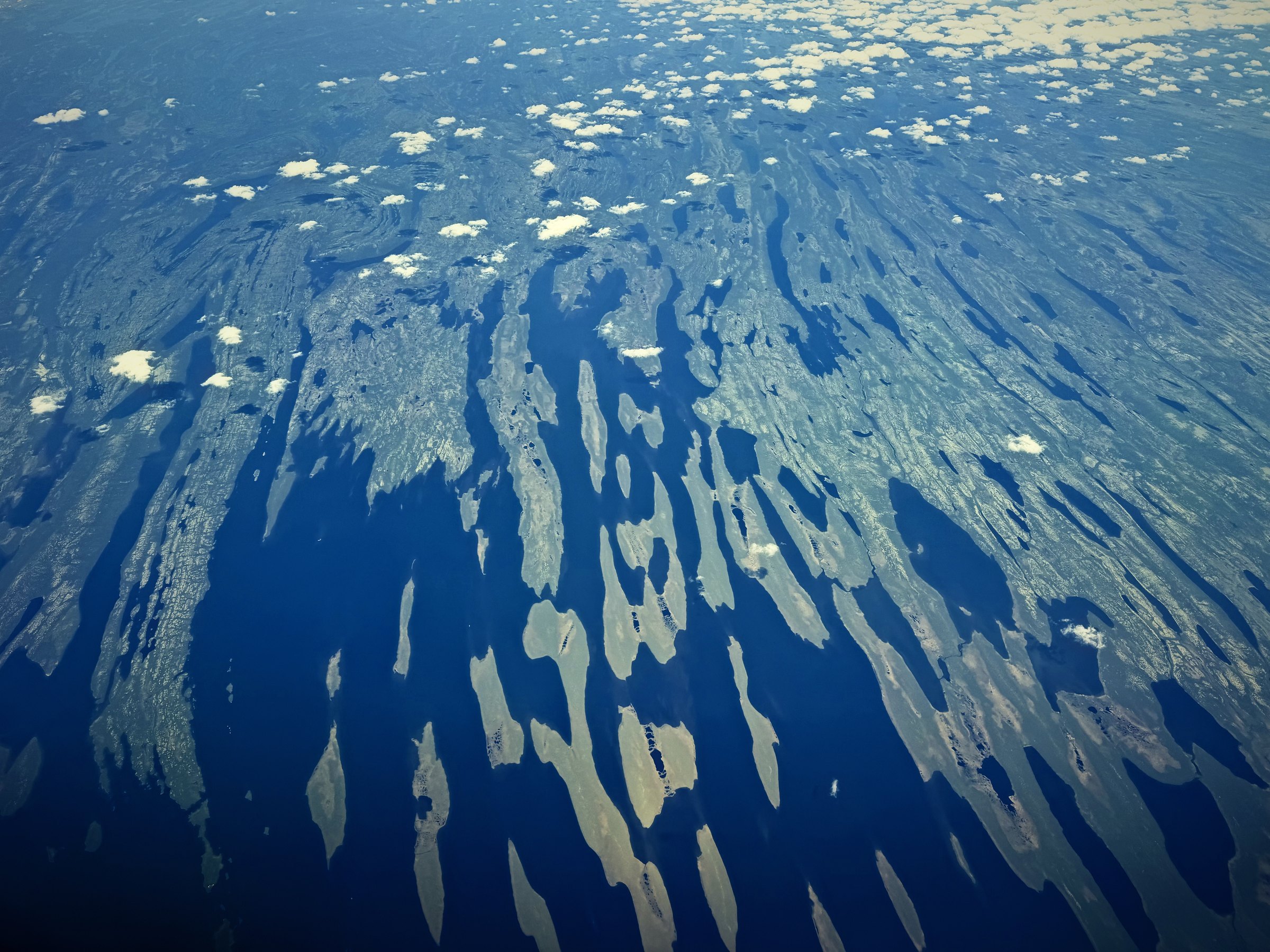 Aerial view of light and shadow breaking the land below into blue and cream shapes.
