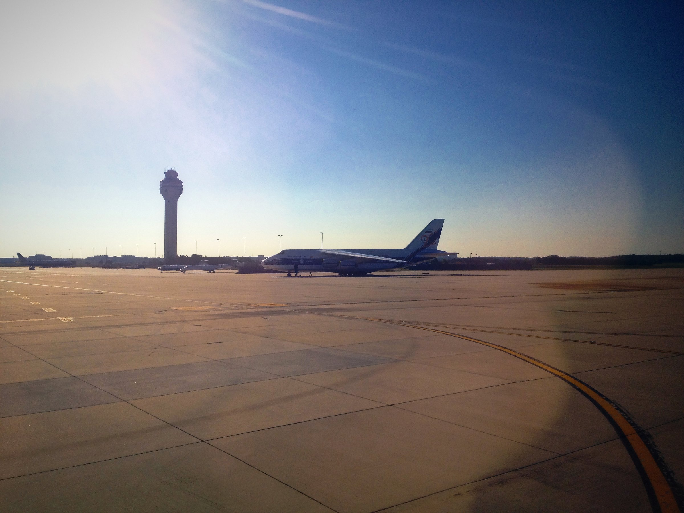 Airport control tower over a wide, empty apron in early morning light.