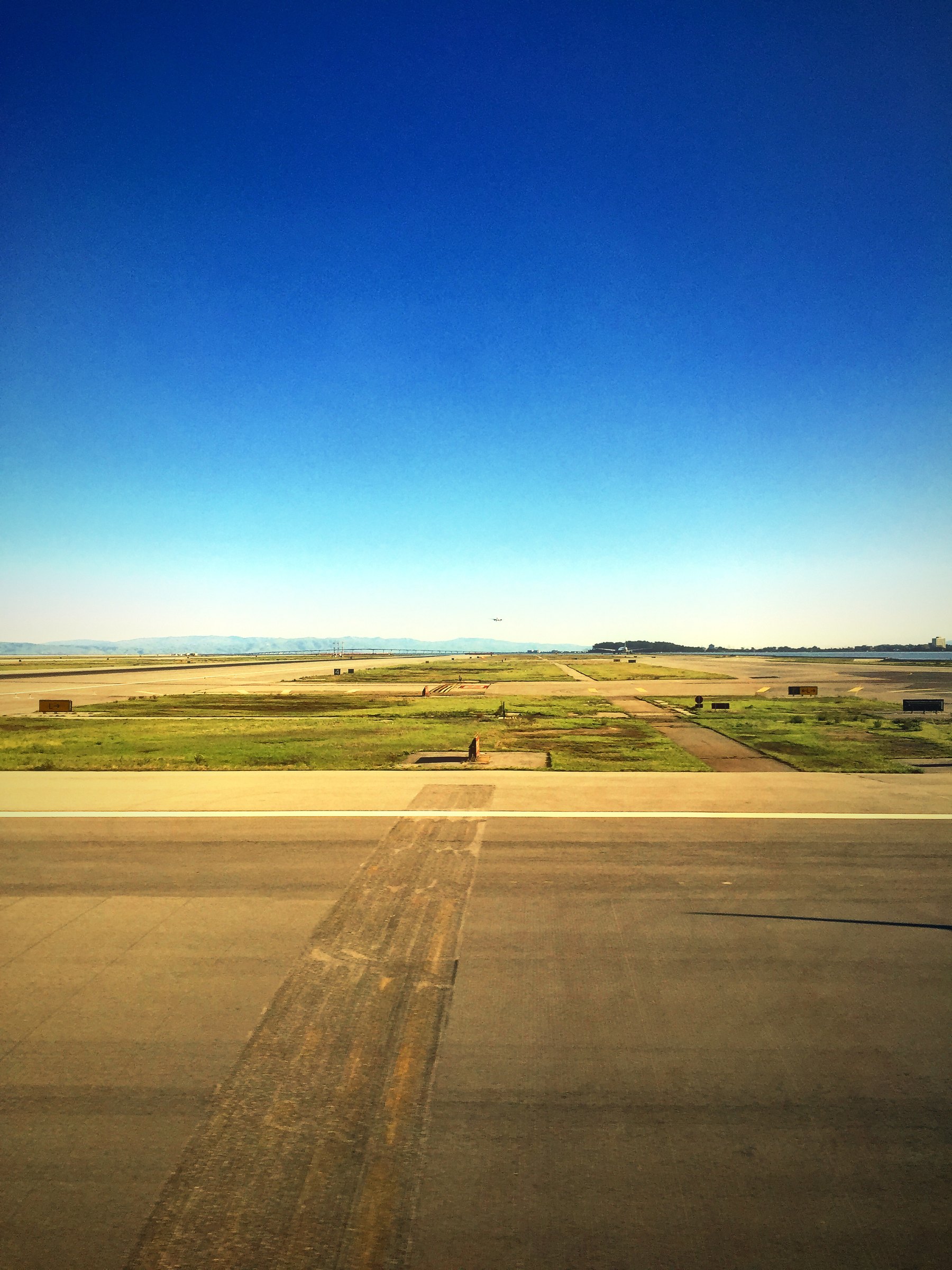 Airport taxiway and grass under a cloudless deep blue sky.