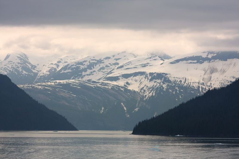 V-shaped fjord gate opening to distant snow-capped peaks.
