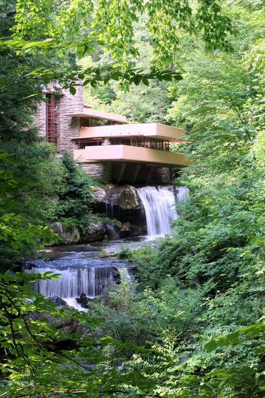 Fallingwater house cantilevered over a leafy summer waterfall.