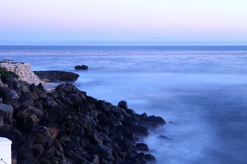 Twilight rocky overlook with sandbags and smoothed blue water.