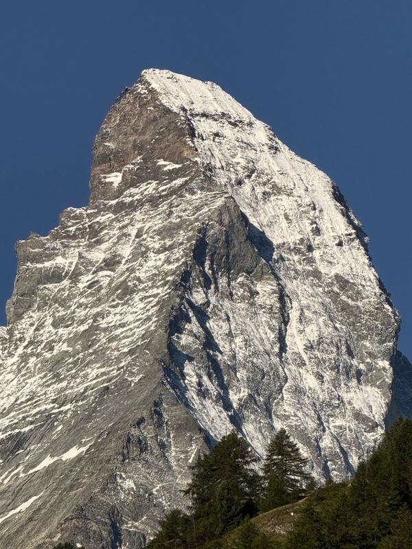 Close crop of steep triangular rock face with snow patches.