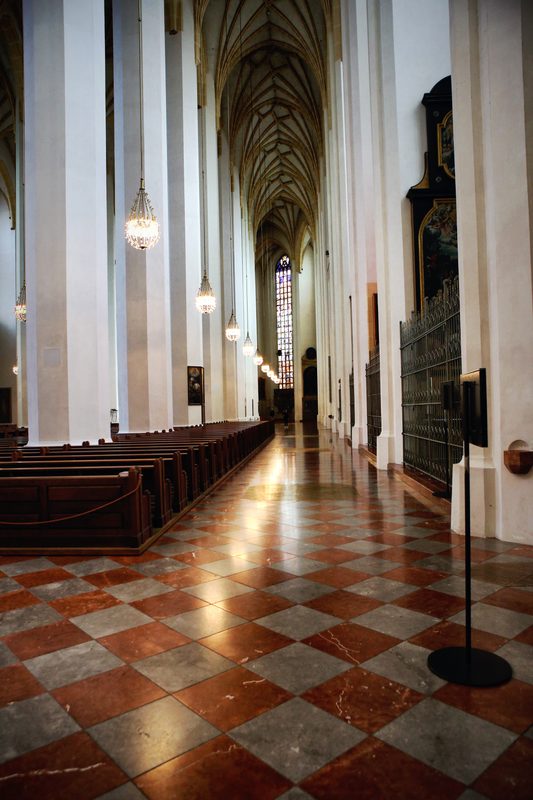 A red-and-white chequered floor running between white church columns.