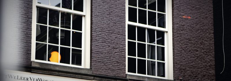 A dark brick facade with white sash windows and a single lit pane.