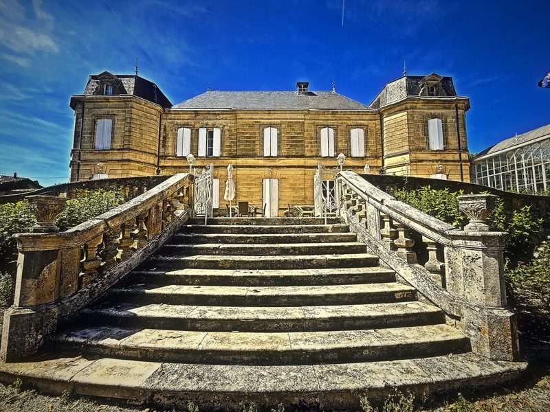 A grand double flight of stone steps rising to a pale château under a deep blue sky.