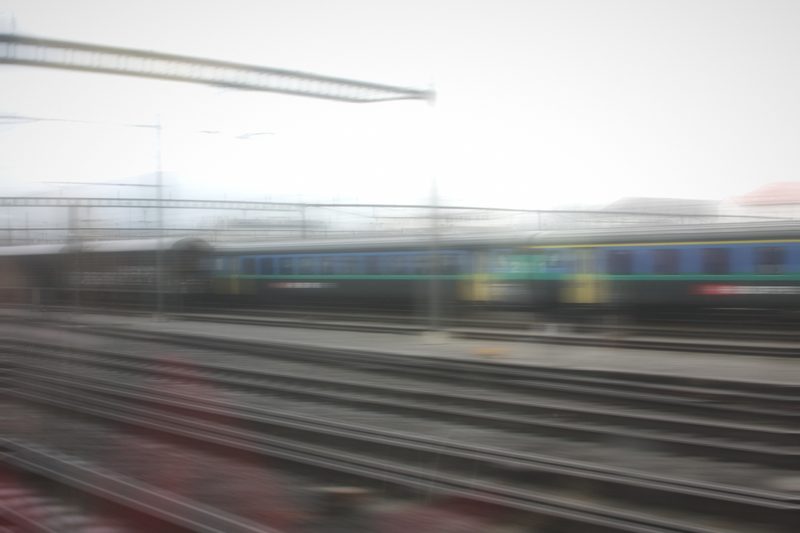 Pale horizontal blur of blue and yellow coaches beside the tracks.