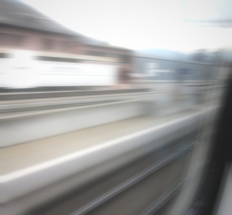 Soft white streaks of a passing train against a grey sky.