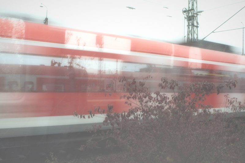 Soft red and white blur of a train with a field in front.