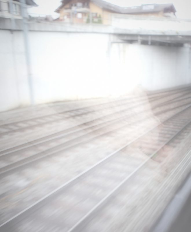 Bright mist falling across tracks below a concrete wall.
