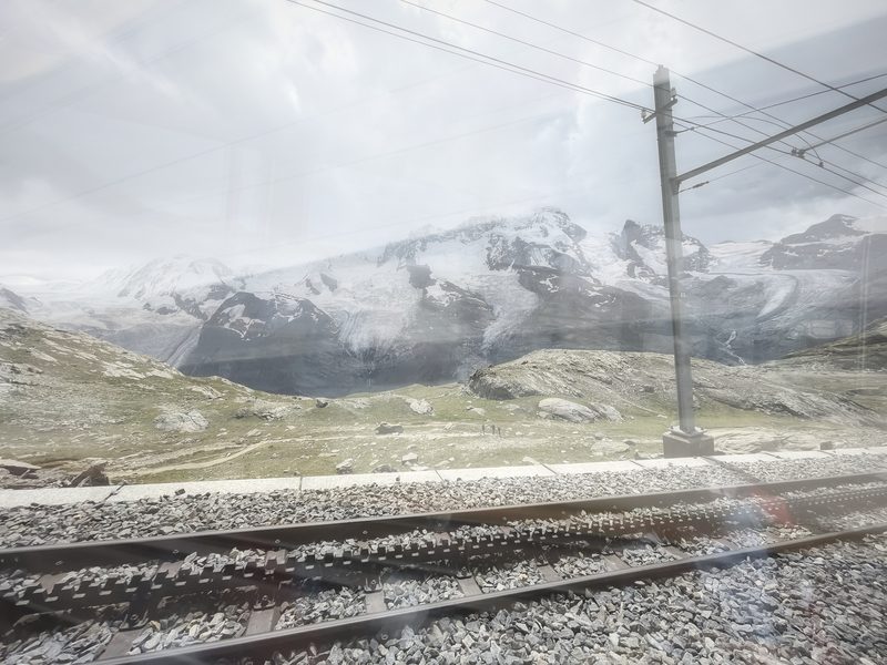 Double exposure of snowy peaks and railway tracks in pale light.