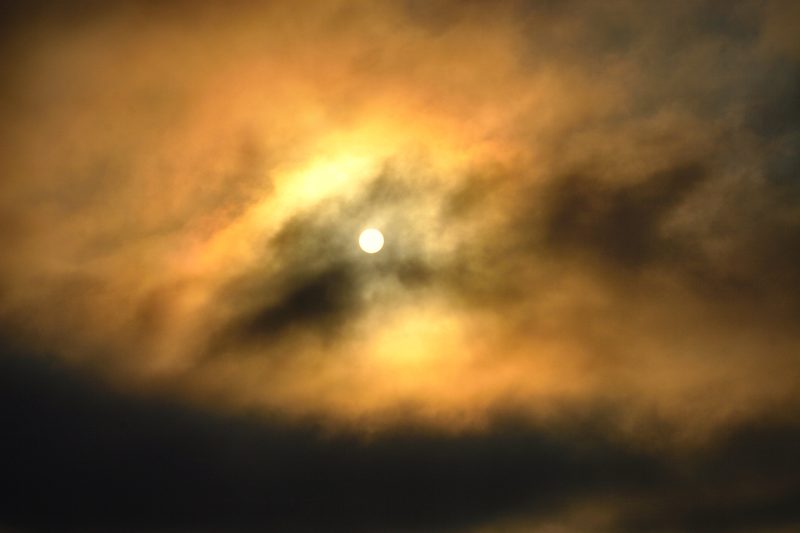 A moon breaking through swirling clouds lit gold and silver around it.