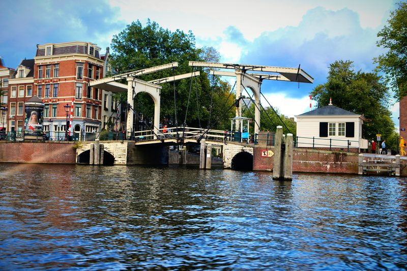 A white wooden drawbridge spanning a canal between brick houses.