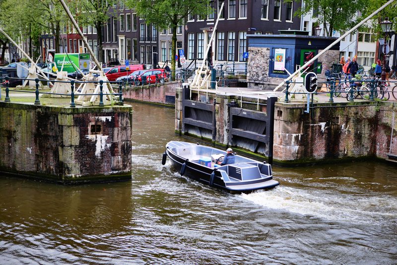 A small motorboat cutting a white wake through a canal lock.