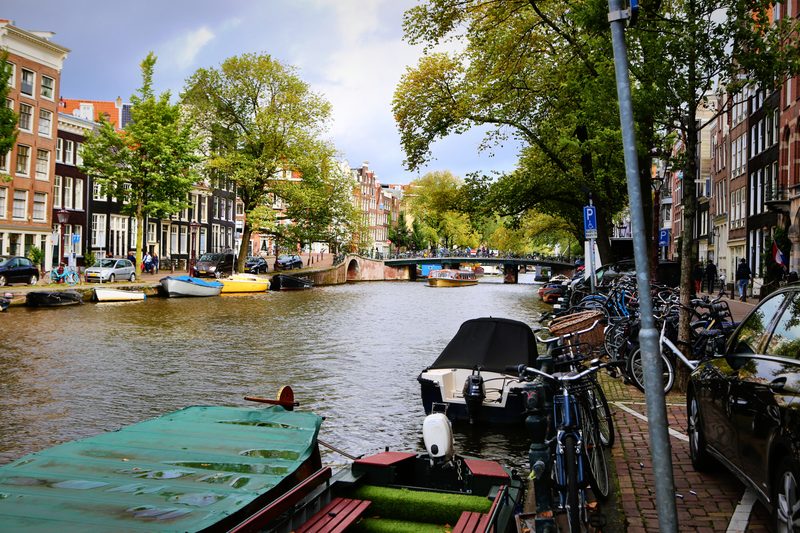 Bicycles locked along a canal railing above moored boats.
