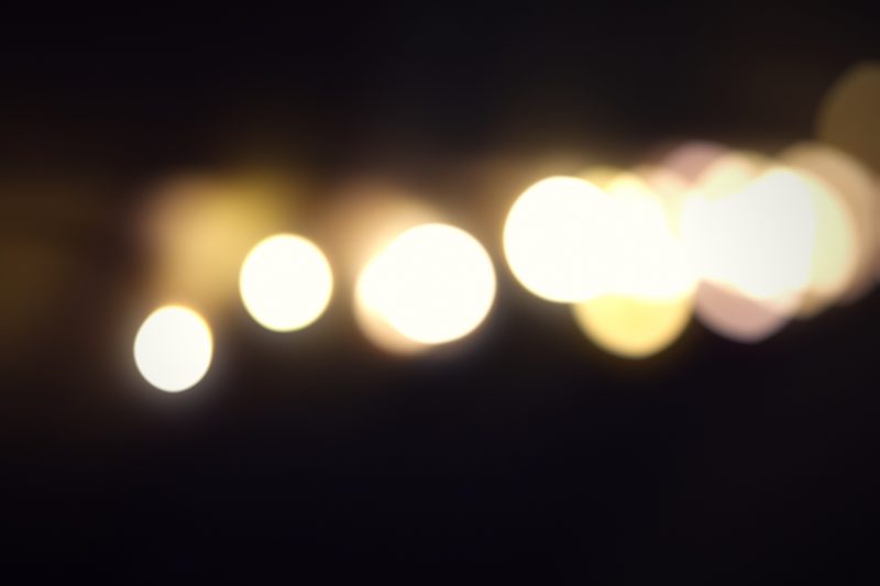 A row of warm lights dissolved into soft gold circles on black.