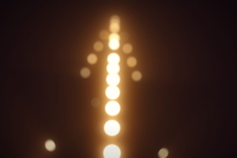 Vertical line of glowing orbs rising through darkness.