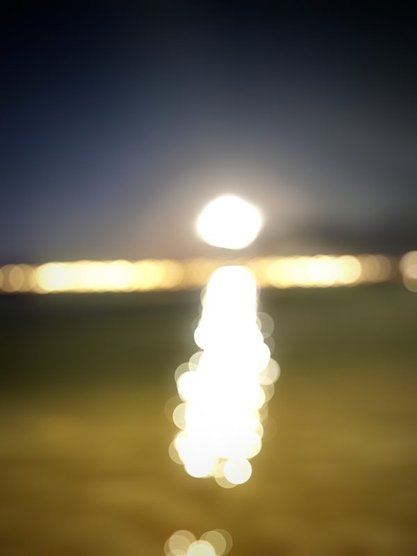 Path of glittering light on water under a pale horizon.