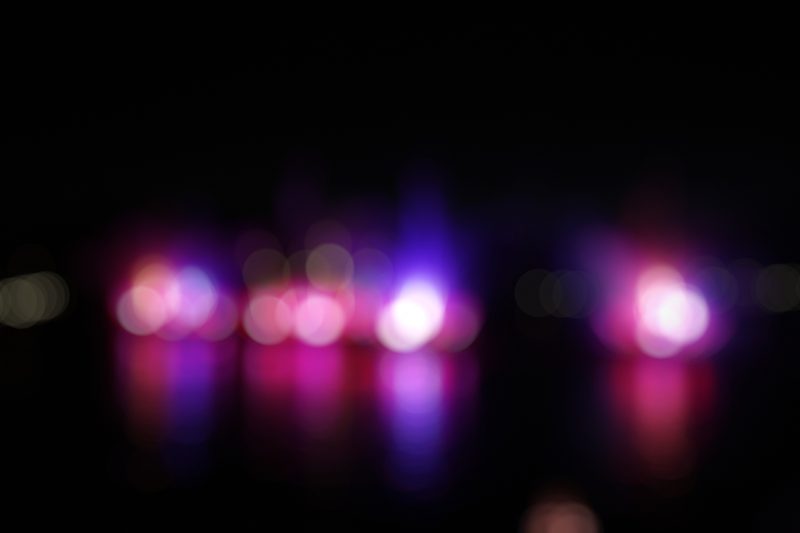 Row of pink and violet lights blurred into soft circles on black.