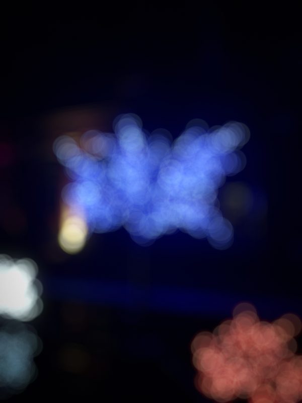 Blue holiday lights in a tree shape with soft red glow below.