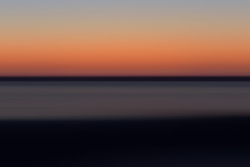 Minimal color field with a single ember-orange band between dusk blue and dark water.