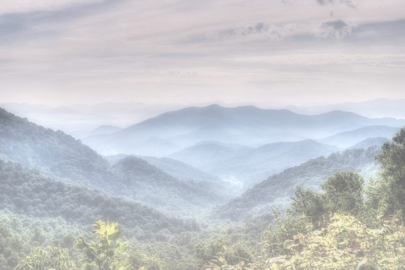 Pale high-key mist over layered blue mountain hollows.