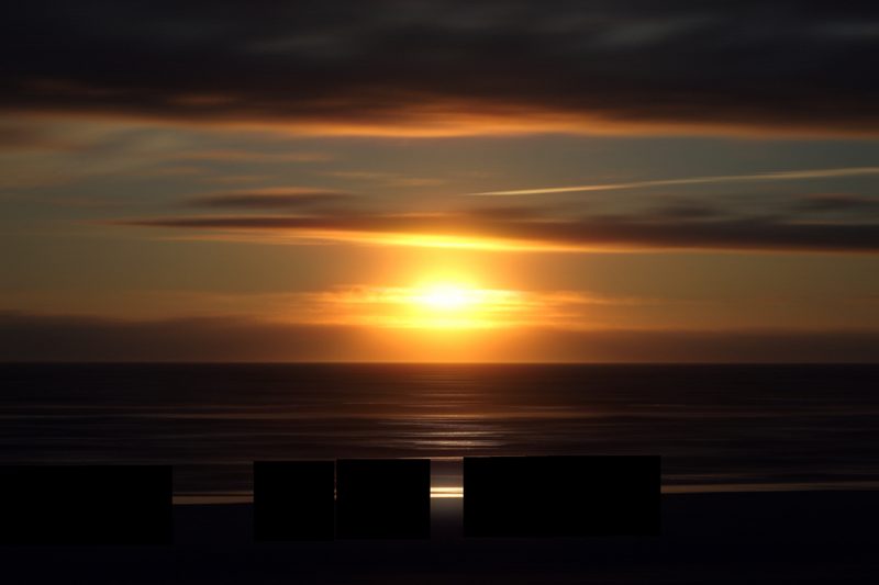 Ocean sunset streaked sideways into ribbons of gold and dark blue.