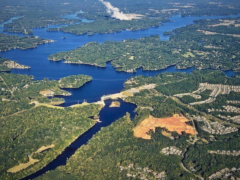 An aerial view of a reservoir branching like veins through green forest.