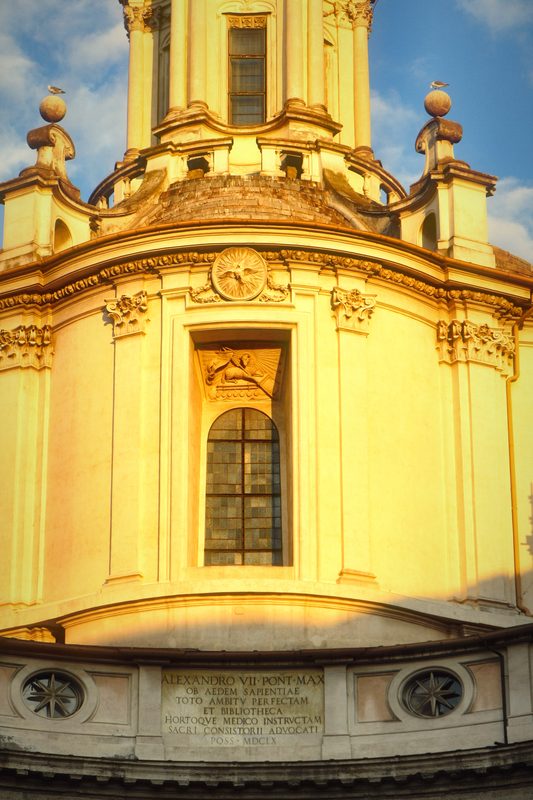 Close view of the curved ochre facade and lantern of Sant'Ivo.