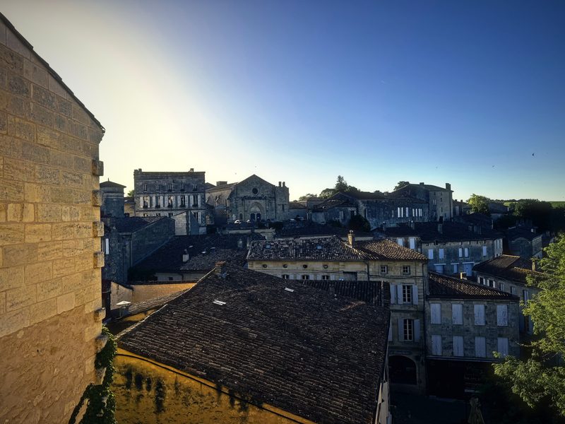 Old tiled rooftops and stone houses spreading below a bright, low morning sun.