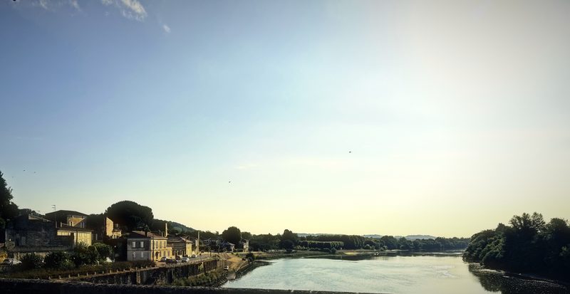 The Dordogne at Castillon-la-Bataille in early sun, with riverside houses and trees catching the light.