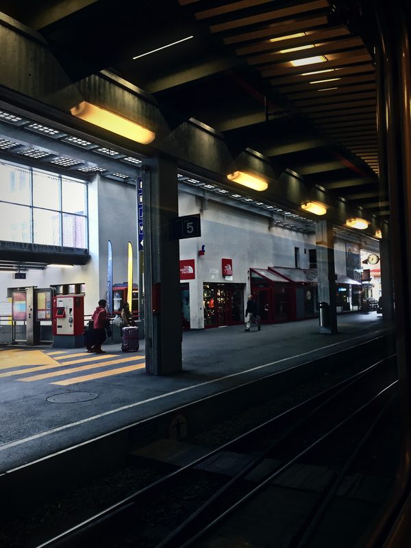 Dark station platform under a deep canopy with warm lights.