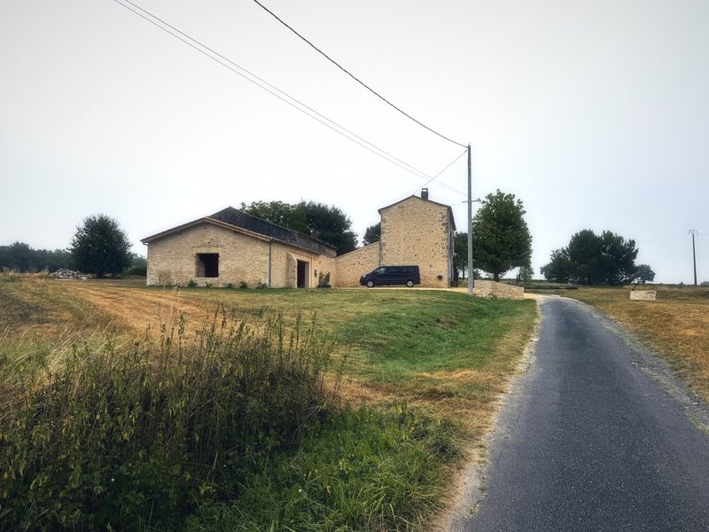 A stone farmhouse at the end of a narrow road, wrapped in soft morning mist.