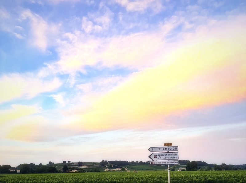 Pink and gold sunset clouds streaming over a flat line of fields.