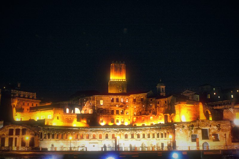 The forum and medieval tower lit gold against the night.