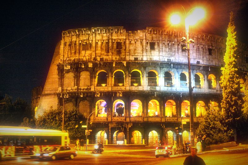 The Colosseum at night with a bright street lamp in front.